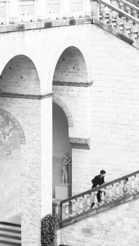Eine Person geht eine Treppe mit weißen Bögen im Hintergrund hinauf.