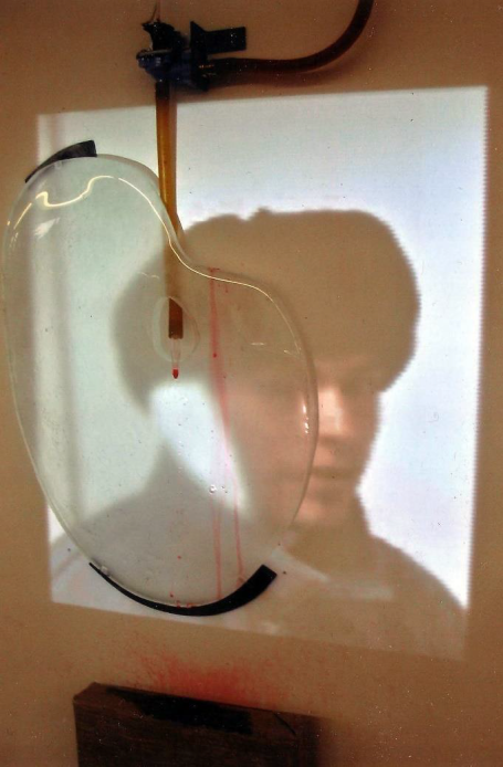 Ein transparentes Objekt projiziert das Gesicht einer Person an die Wand.