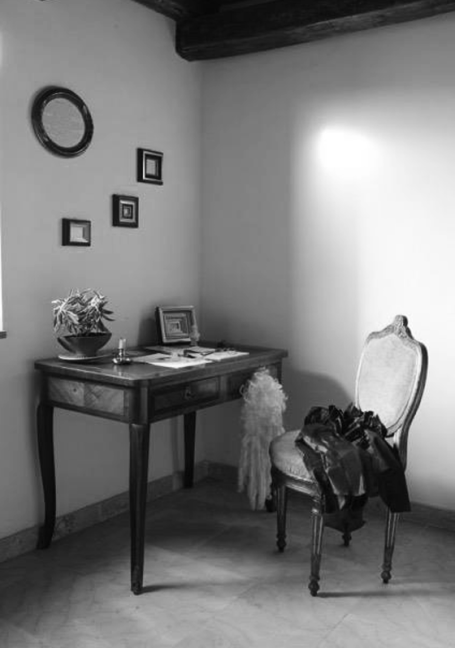 Ecke eines Raumes mit Schreibtisch, Stuhl, Bildern an der Wand und Pflanzen.