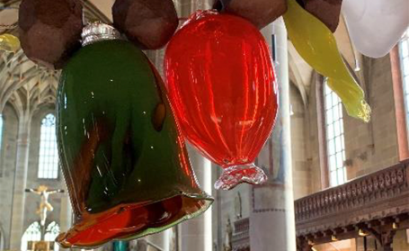 Bunte, gläserne Weihnachtsbaumkugeln in leuchtenden Farben hängen dekorativ.