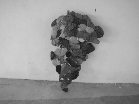 Eine skulpturale Anordnung aus verschiedenen Plastik Überresten an einer Wand.