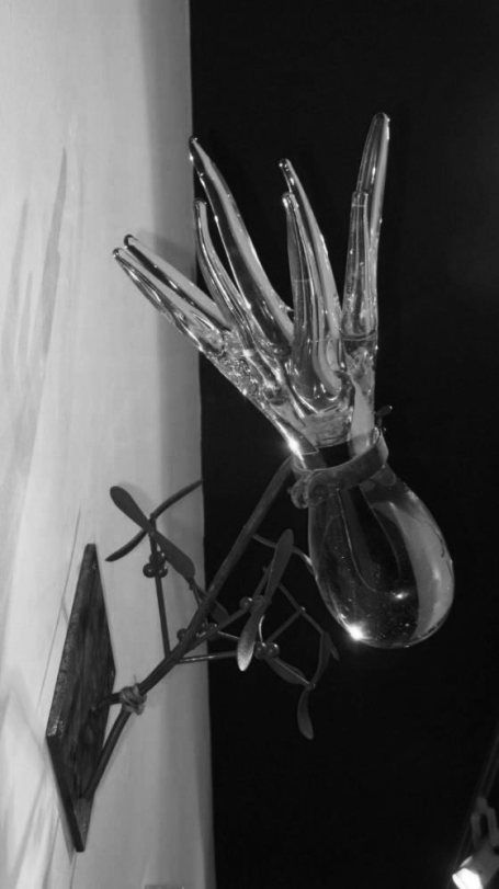 Transparente Skulptur einer Blume mit kunstvollen Blütenblättern, an der Wand befestigt.