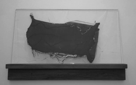 Abstrakte Skulptur aus schwarzem Material in einer transparenten Vitrine.